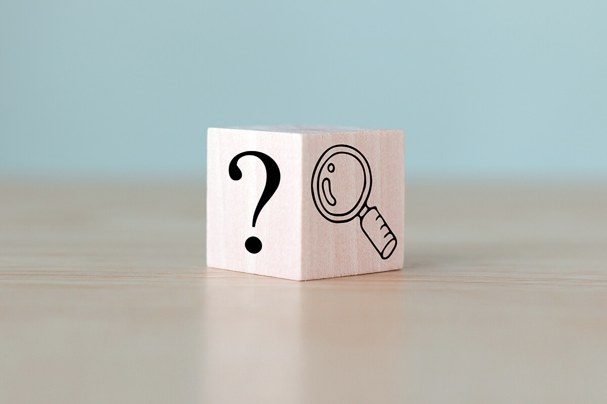 Symbolbild für Hinweis: Holzwürfel mit aufgemaltem Fragezeichen und Lupe, Fotocredit iStock.com / tsingha25 Würfel mit Fragezeichen und Lupe