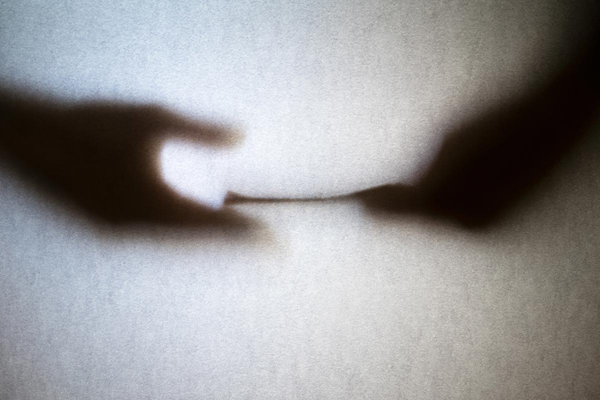 Symbolbild für Korruption / Amtsdelikte: Schatten von zwei Händen mit Übergabe eines Kuverts, Fotocredit iStock.com / Ja'Crispy Schatten von zwei Händen mit Übergabe eines Kuverts